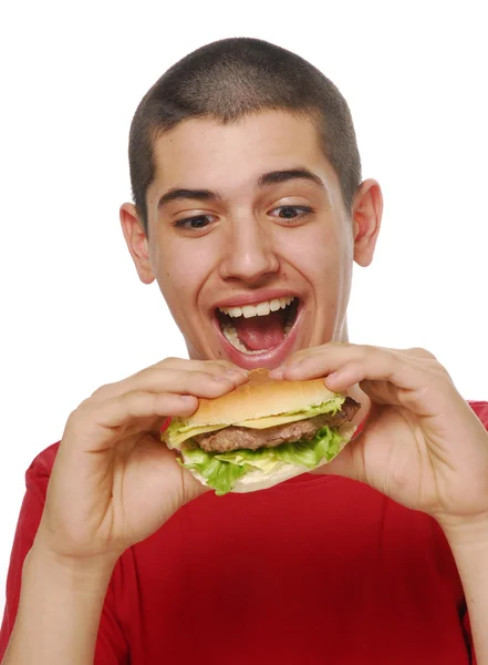 Junges Kind hält und isst einen Hamburger auf weißem Hintergrund. — Stockfoto