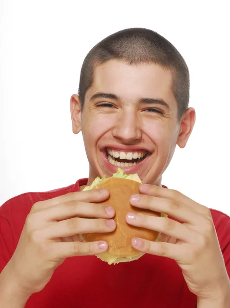 Giovane bambino che tiene e mangia un hamburger su sfondo bianco . — Foto Stock