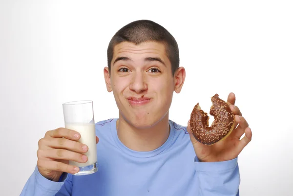 Ragazzino che tiene e mangia ciambelle al cioccolato e beve latte su sfondo bianco . — Foto Stock