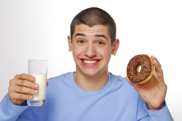 Liten pojke hålla och äta en choklad donuts och dricka mjölk på vit bakgrund. — Stockfoto