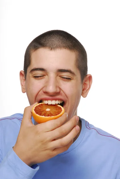 Rapaz segurando e comendo laranjas frescas . — Fotografia de Stock