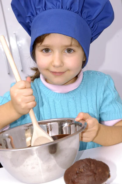 Malá holčička vaření čokolády v kitchen.little holka pomocí víčko kuchař a vaření v kuchyni. — Stock fotografie