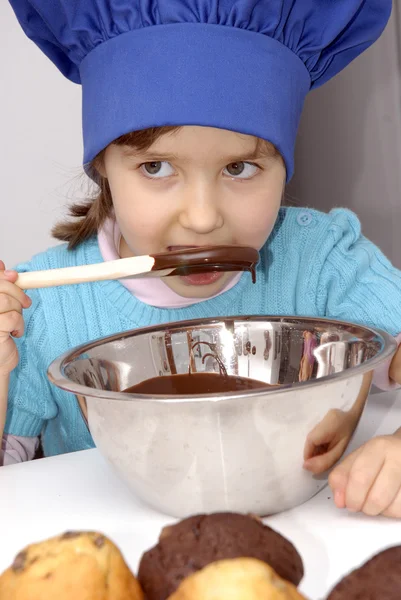 Küçük kız Şef kap kullanarak ve bir mutfakta yemek kitchen.little bir kız çikolata yemek. — Stok fotoğraf