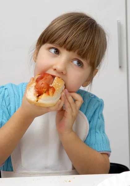 Liten flicka äter en varm dog.kid äta varmkorv. — Stockfoto