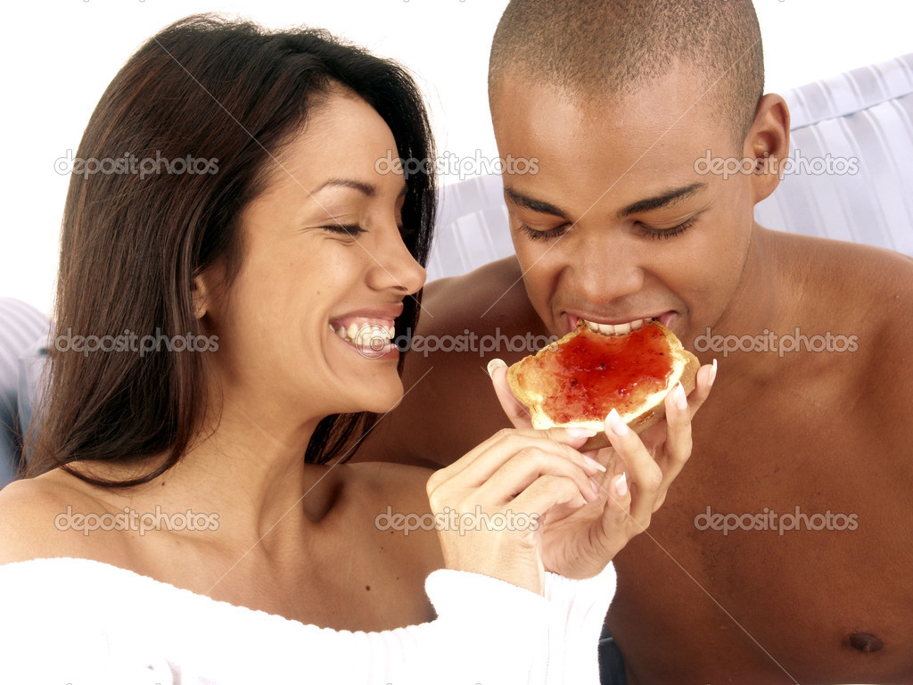 Hispanic young couple eating marmalade bread.