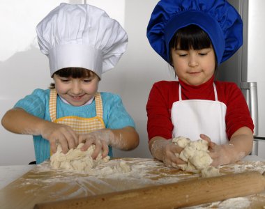iki küçük kız birlikte kitchen.little çocuk bir mutfakta pizza pişirme.