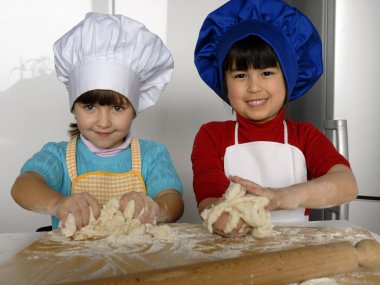iki küçük kız birlikte kitchen.little çocuk bir mutfakta pizza pişirme.