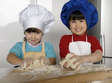 iki küçük kız birlikte kitchen.little çocuk bir mutfakta pizza pişirme.