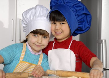 iki küçük kız birlikte kitchen.little çocuk bir mutfakta pizza pişirme.