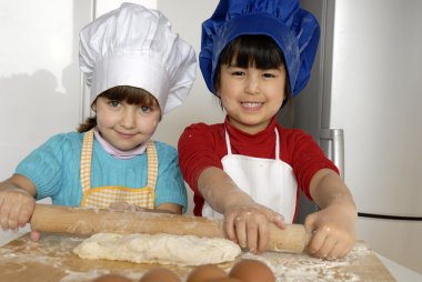 iki küçük kız birlikte kitchen.little çocuk bir mutfakta pizza pişirme.