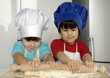 iki küçük kız birlikte kitchen.little çocuk bir mutfakta pizza pişirme.