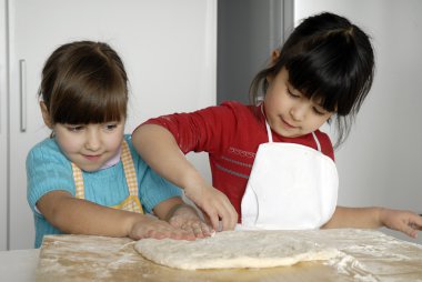 iki küçük kız birlikte kitchen.little çocuk bir mutfakta pizza pişirme.