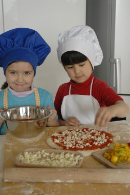 iki küçük kız birlikte kitchen.little çocuk bir mutfakta pizza pişirme.