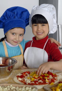 iki küçük kız birlikte kitchen.little çocuk bir mutfakta pizza pişirme.