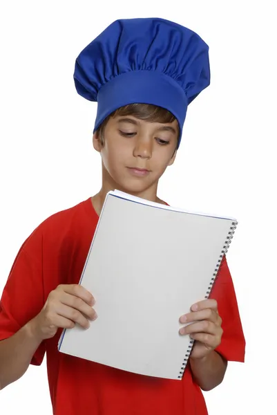 Kleine jongen chef-kok houden een opmerking boek op witte achtergrond. — Stockfoto