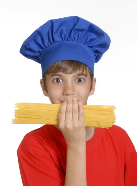 Piccolo bambino chef che tiene un mucchio di spaghetti grezzi su sfondo bianco. bambino che tiene la pasta . — Foto Stock