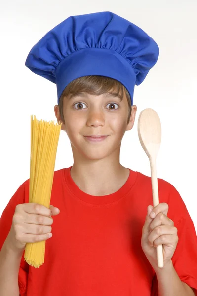 Piccolo bambino chef che tiene un mucchio di spaghetti grezzi su sfondo bianco. bambino che tiene la pasta . — Foto Stock