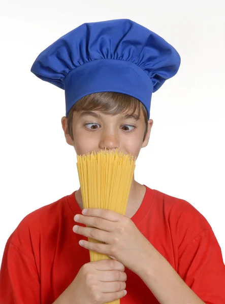 Kleine chef-kok jongen houden van een bos van ruwe spaghetti op witte background.little kind bedrijf pasta. — Stockfoto