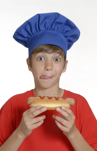 Kleine chef-kok jongen hotdog, kid hotdog eten houden. — Stockfoto