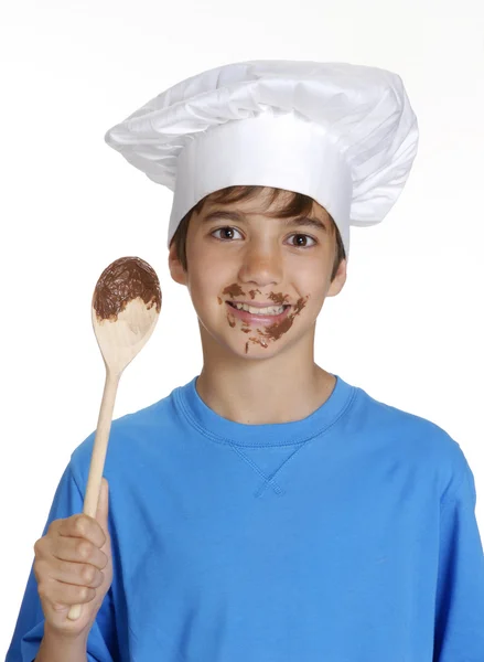 Niño comiendo crema de chocolate y sosteniendo una cuchara de madera . —  Fotos de Stock