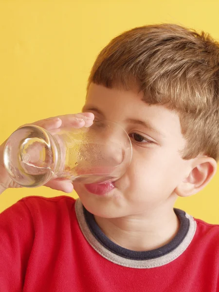 Little kid drinking a glass of water. — Stock Photo, Image