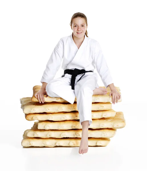 Martial arts girl sitting on a stack of cookies. karate girl portrait.Martial arts and karate kid portrait. — Stock Photo, Image