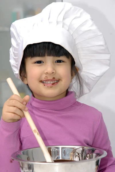 Malá holčička vaření čokolády v kitchen.little holka pomocí víčko kuchař a vaření v kuchyni. — Stock fotografie