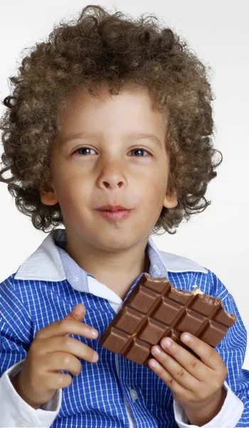 Klein kind eten van chocolade, chocolade bar bedrijf. — Stockfoto