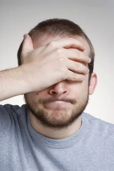 Expressieve jonge man die betrekking hebben op zijn ogen. — Stockfoto