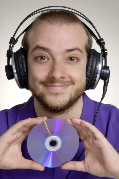 Genç disk jokey kulaklık kullanarak bir kompakt disc.young adam tutarak. — Stok fotoğraf