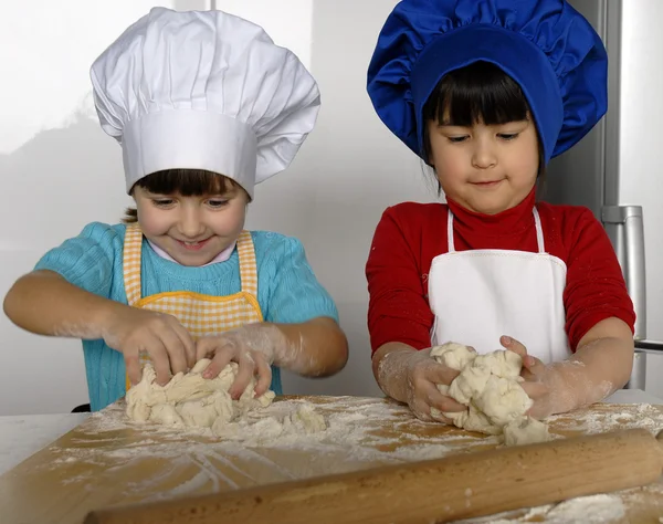 Dos niñas cocinando una pizza en una cocina.Un niño pequeño en una cocina juntos . —  Fotos de Stock