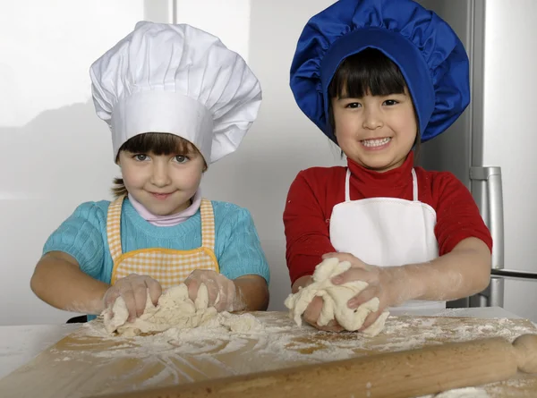 Dos niñas cocinando una pizza en una cocina.Un niño pequeño en una cocina juntos . —  Fotos de Stock