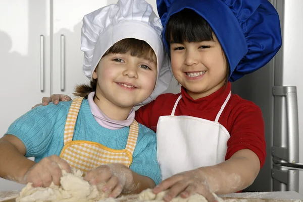 iki küçük kız birlikte kitchen.little çocuk bir mutfakta pizza pişirme.