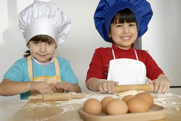 iki küçük kız birlikte kitchen.little çocuk bir mutfakta pizza pişirme.