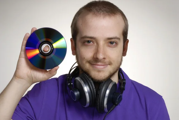 Unga discjockey innehar en kompakt disc.young man använder hörlurar. — Stockfoto