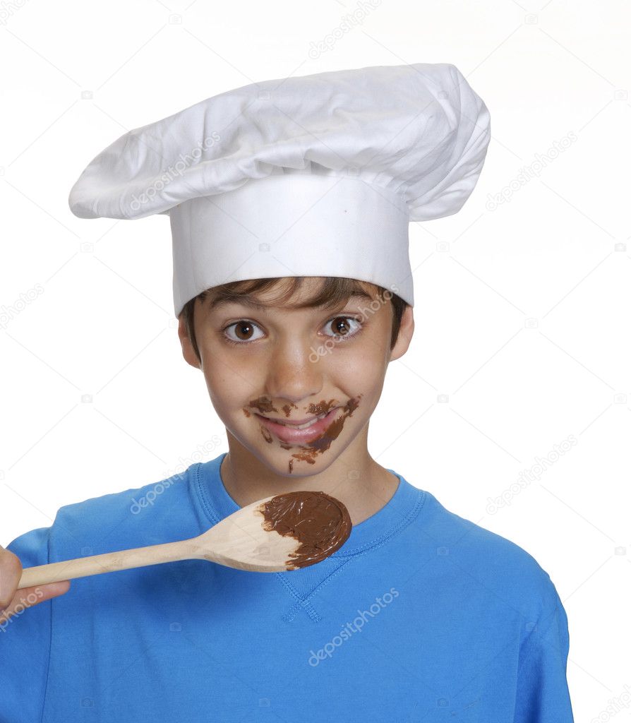 Little kid eating chocolate cream and holding a wood spoon.