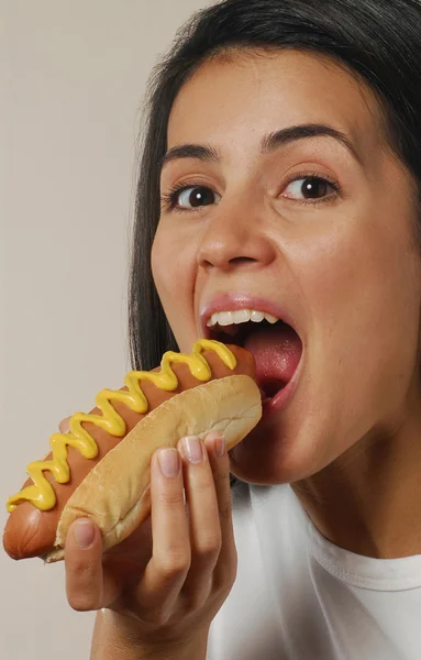 Mujer joven comiendo perrito caliente . — Foto de Stock