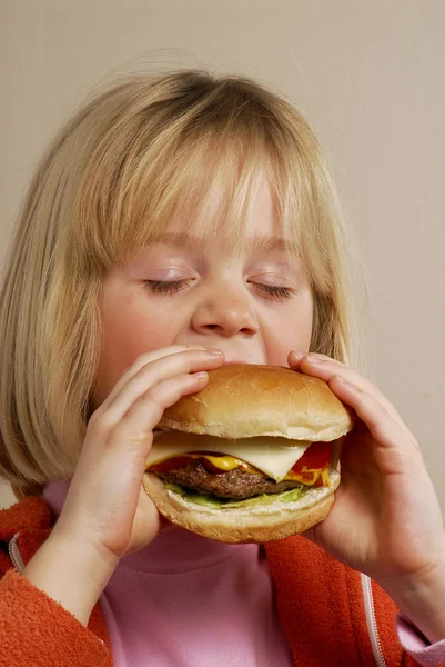 ハンバーガーを食べて少女. — ストック写真