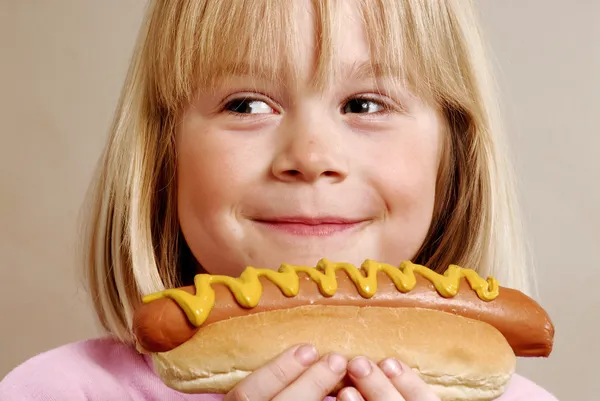 小さな女の子のホットドッグを食べる — ストック写真