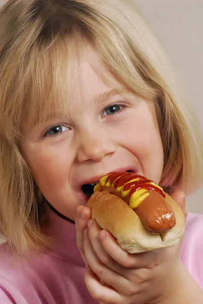 小さな女の子のホットドッグを食べる — ストック写真