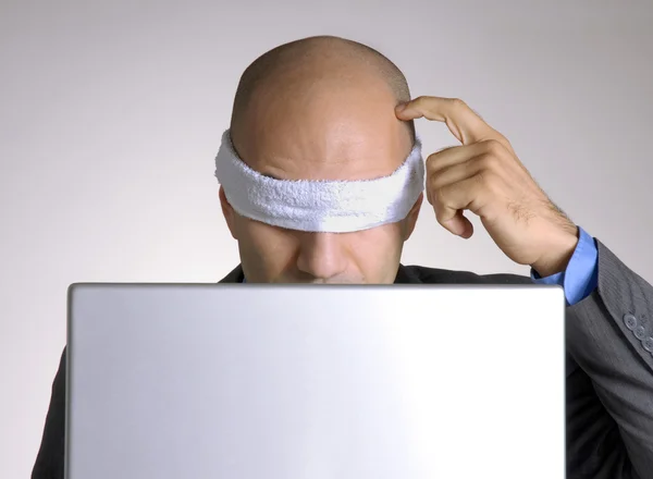Verward geblinddoekte kale hoofd man die met een computer. — Stockfoto
