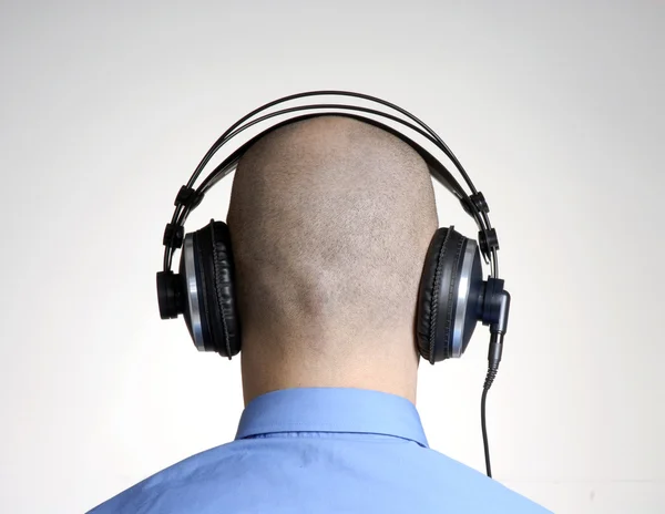 Rear view from an adult bald head man using headphones. Stock Photo