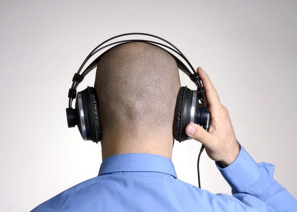 Rear view from an adult bald head man using headphones. Stock Photo