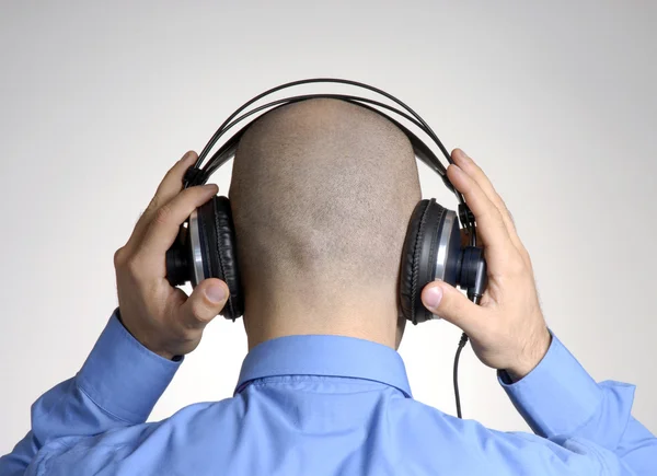 Rear view from an adult bald head man using headphones. Stock Picture