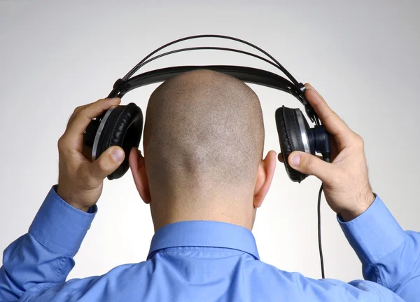 Rear view from an adult bald head man using headphones. Stock Image