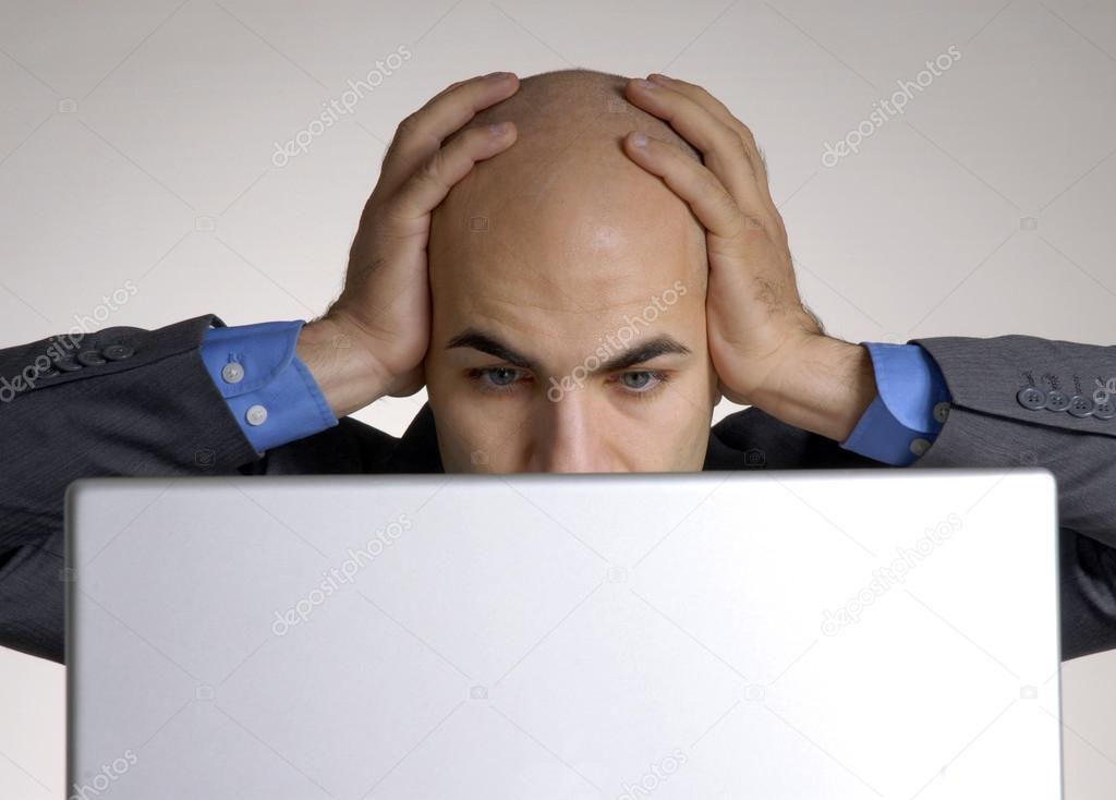 Stressed and confused bald head man working on computer.