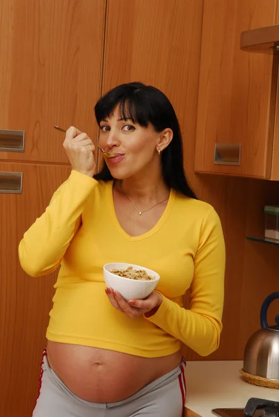 Zwangere vrouw eten granen kom bij keuken. — Stockfoto
