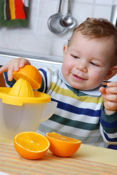 Kleines Baby presst Orangensaft. — Stockfoto