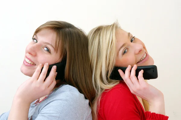 Twee jonge vrouwen samen praten op mobiele telefoon. — Stockfoto