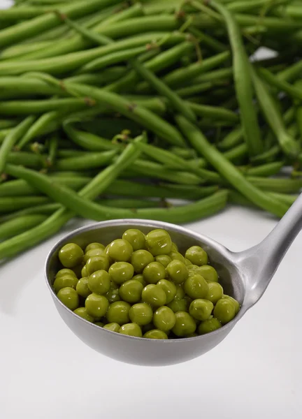 Metallic spoon with boiled fresh green peas on it. — Stock Photo, Image